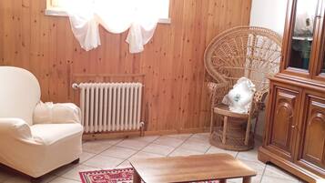Une pièce comprenant une chaise en bois, une table en bois, un radiateur et un tapis à motifs.