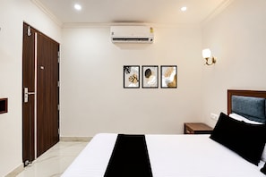 A hotel room with a bed, a wardrobe, an air conditioning unit, and wall-mounted artwork. - Hotel O The Anand Hotel (Zirakpur)