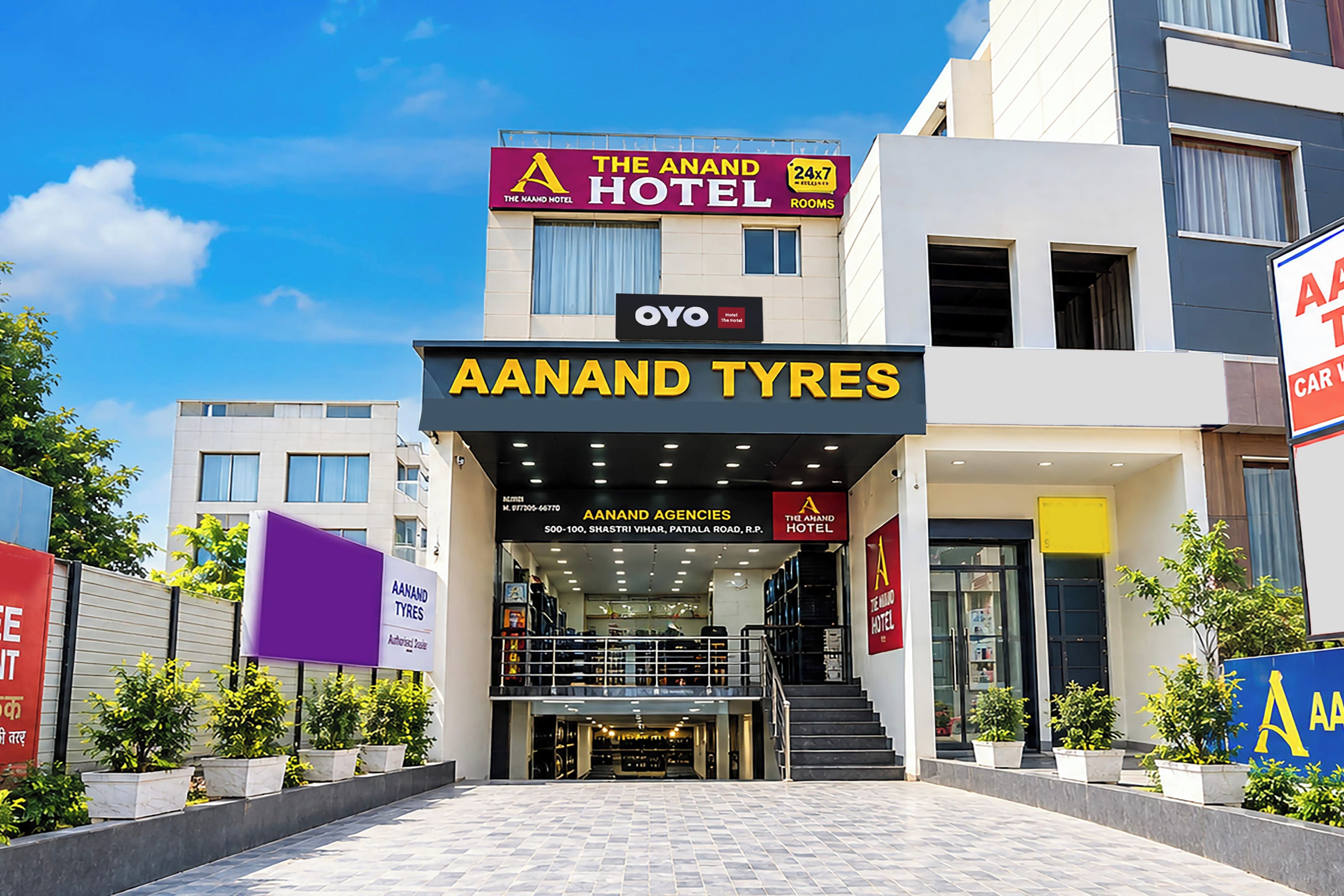 Entrada de un hotel con un letrero que dice 'The Aanand Hotel' y 'Aaanand Tyres' debajo.