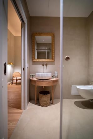 A bathroom with a wooden vanity, a round sink, a mirror with a gold frame, and a separate pedestal sink. - Villa Mabel Boutique Hotel (Taormina)