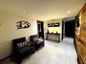 A living room with two sofas, a console table with a lamp, and wall art. - Chalet with Private Spa and Sauna (Morzine)