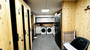 Une cuisine de taille réduite équipée d’un lave-linge, d’un réfrigérateur et d’une chaise.