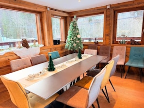 A dining area with a long table, multiple chairs, and a Christmas tree. - Chalet with Private Spa and Sauna (Morzine)