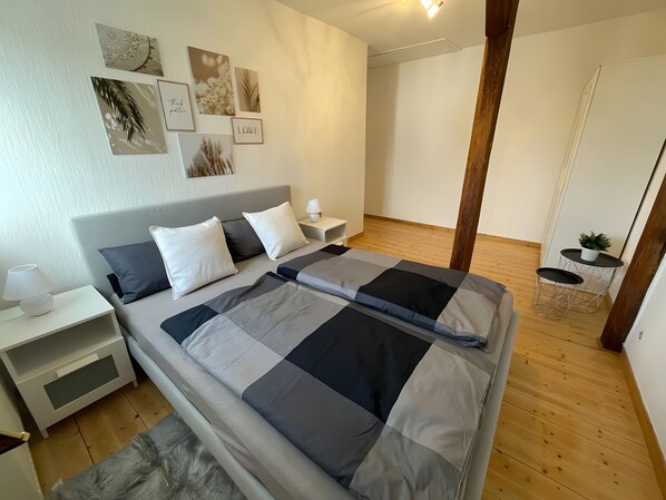 Une chambre à coucher comprenant un lit, des tables de chevet, une commode, une lampe et des œuvres d’art murales.