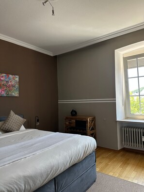 Une chambre à coucher comprenant un lit, une fenêtre, un radiateur et une œuvre d’art accrochée au mur.
