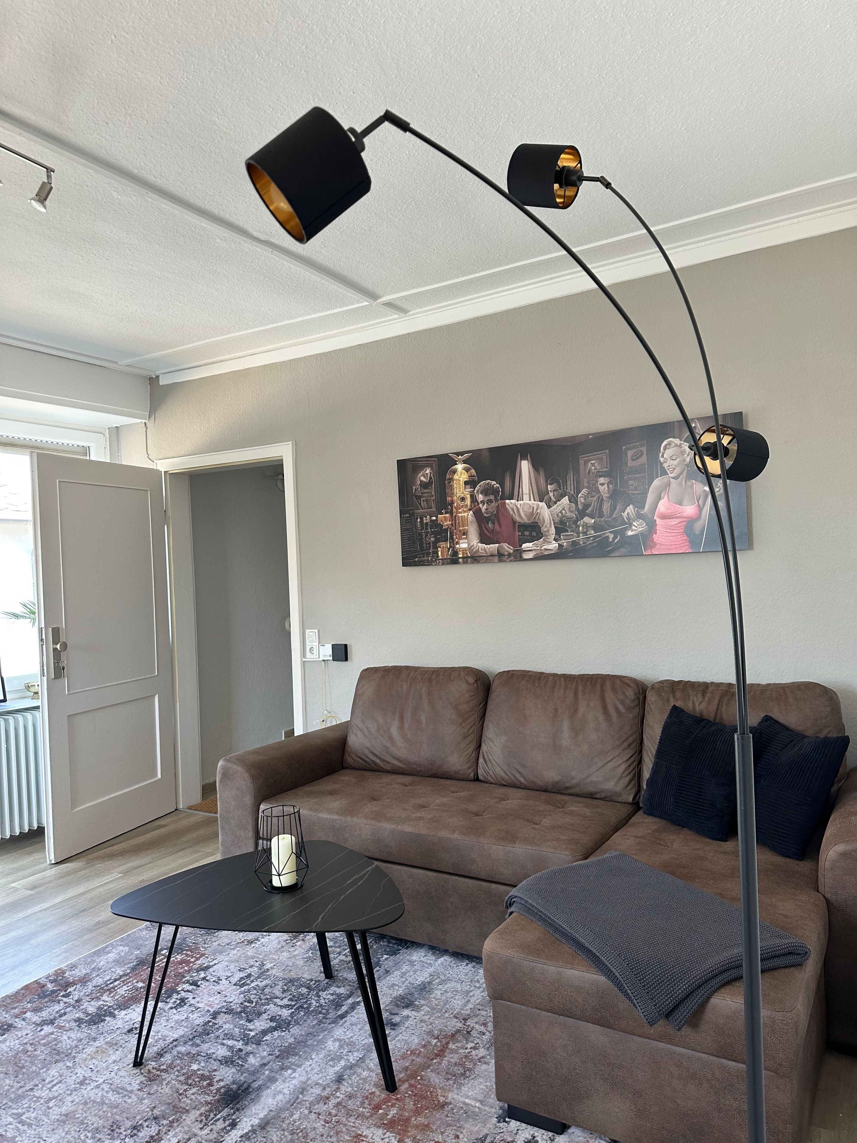 A living room with a brown sofa, a coffee table, and a floor lamp.