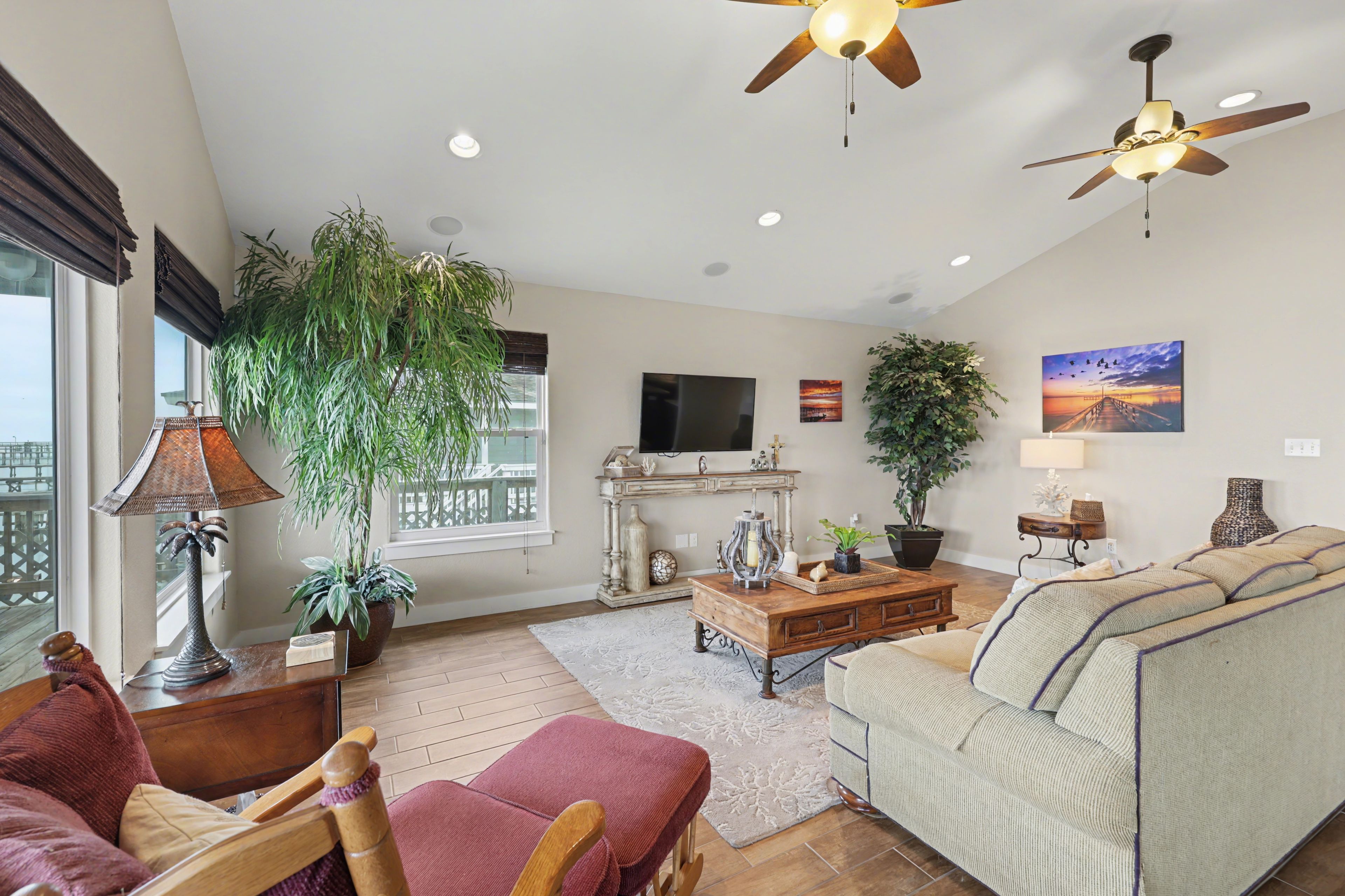A living room with a sofa, chairs, a coffee table, a fireplace, and ceiling fans.