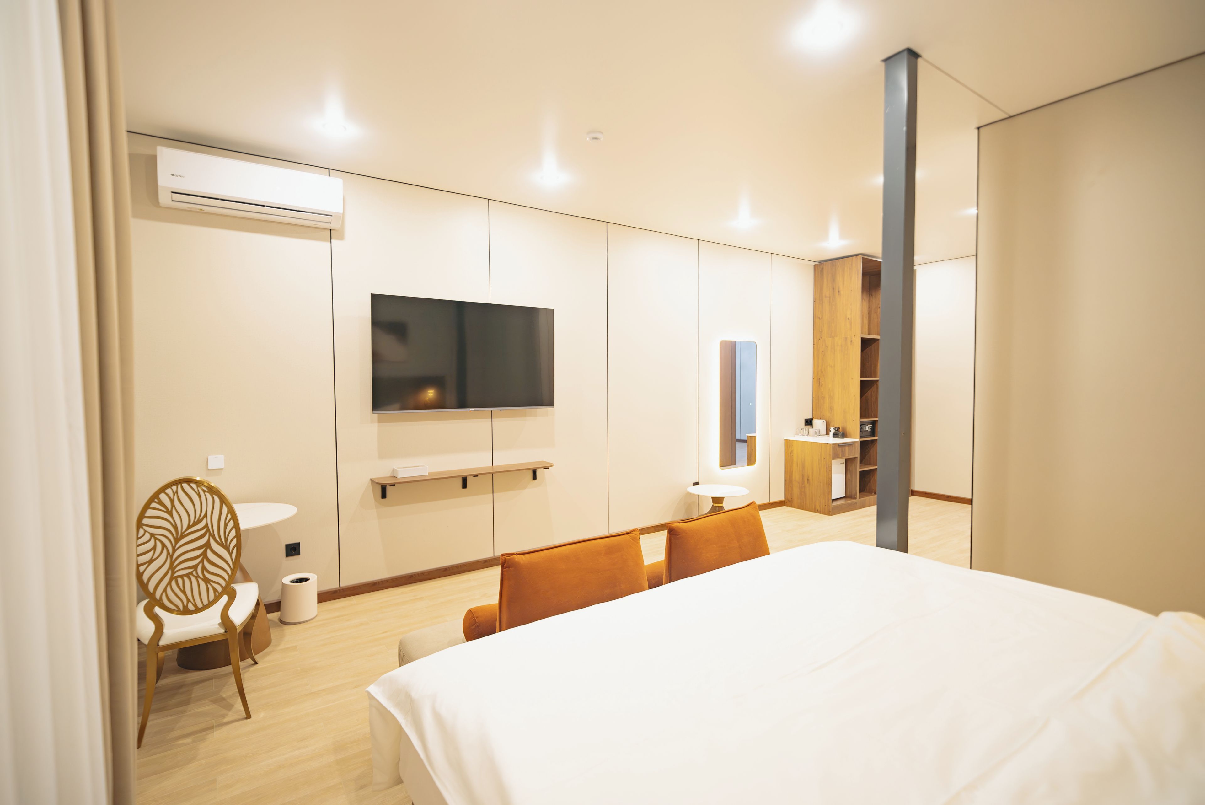 Habitación de hotel con cama, televisor, escritorio y espejo.