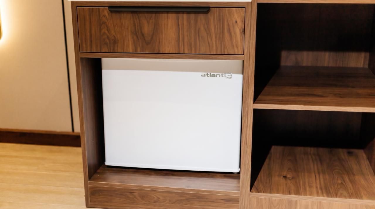 Ein weißer Kühlschrank der Marke 'atlantic' in einem Holzschrank mit einer Schublade.