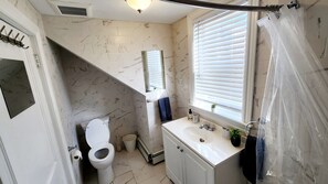 Un bagno con il water, un lavandino e una finestra con persiane.