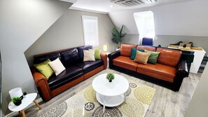 Ein modernes Wohnzimmer mit einem Ecksofa, einem kleinen weißen Tisch und einem dekorativen Teppich.