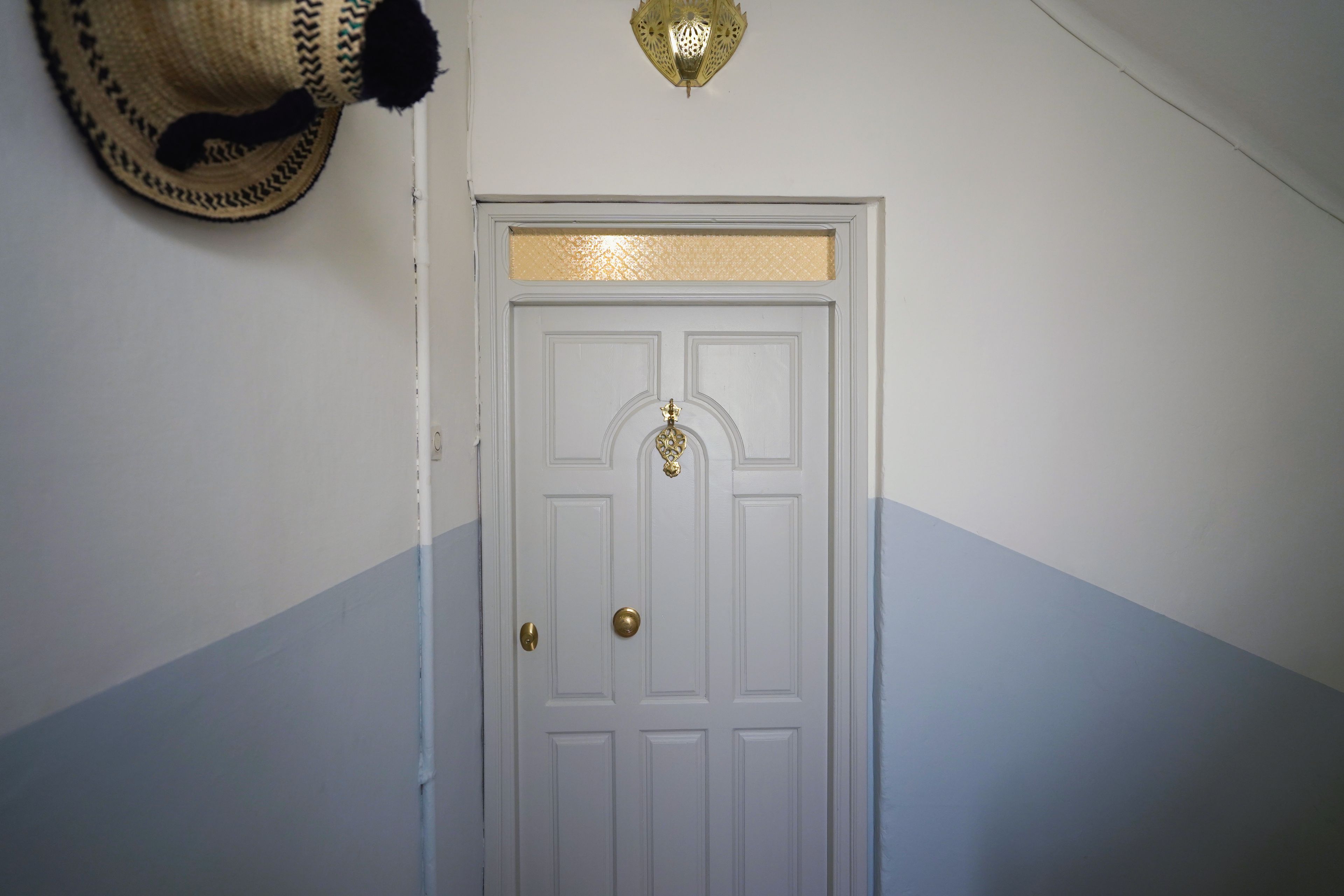 Una puerta blanca con picaporte de latón y una placa decorativa de latón encima.