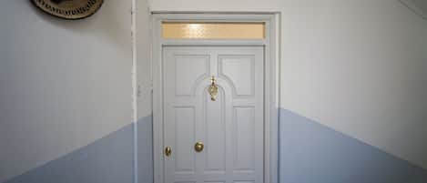 A white door with a brass doorknob and a decorative brass plate above it.
