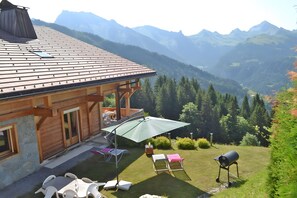 Eine Holzhütte mit einer Terrassenfläche, Sitzgelegenheiten im Freien und einem Grill.