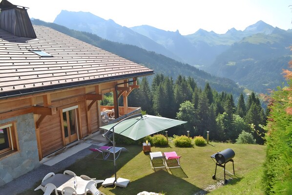 A wooden cabin with a patio area, outdoor seating, and a barbecue grill.