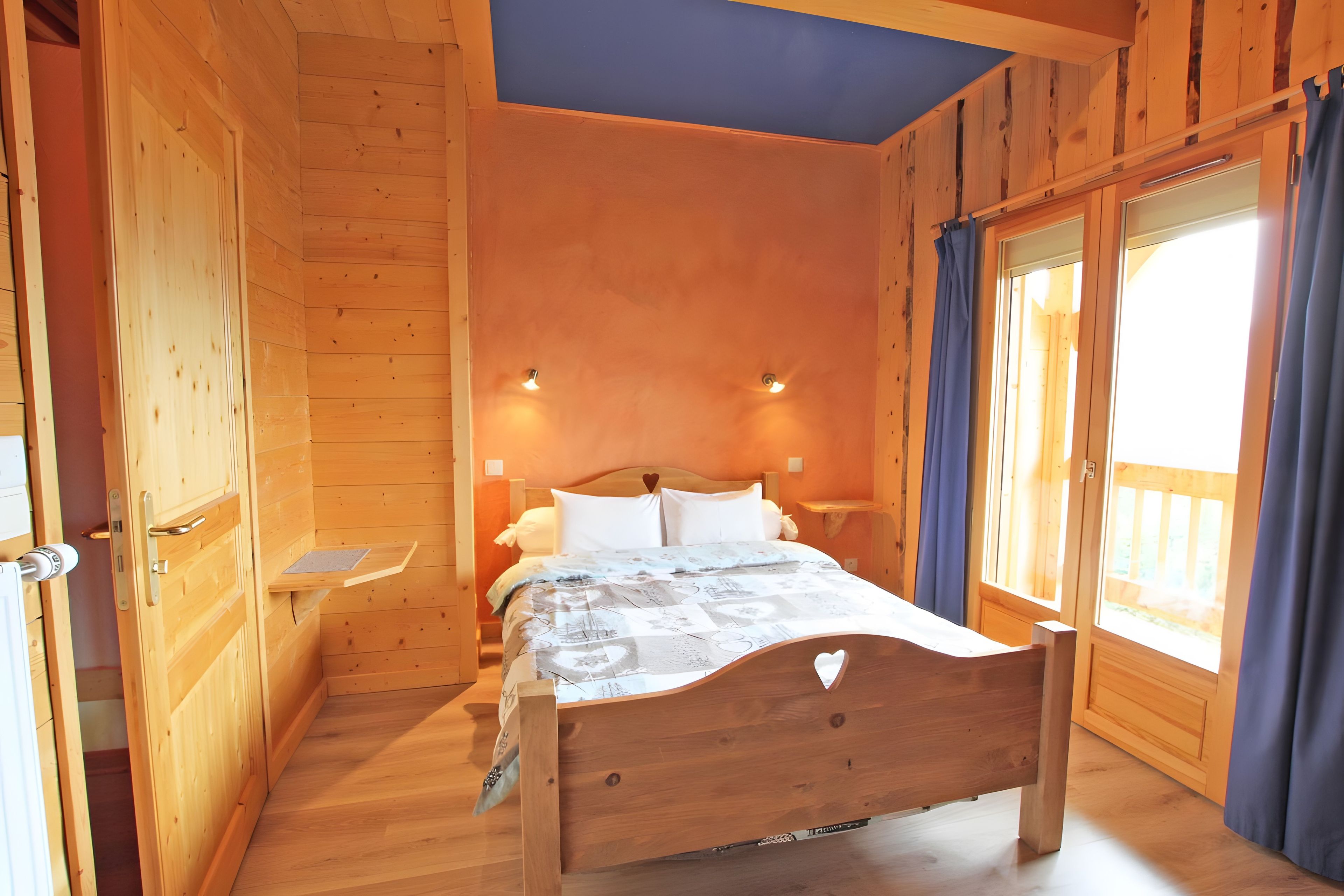 Een kamer met houten vloeren, een bed, een nachtkastje en een raam met gordijnen.