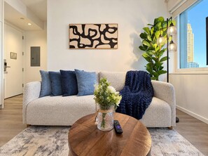 Uma sala de estar moderna com um sofá, uma mesa de centro e um painel decorativo na parede.