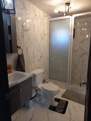 A modern bathroom with a toilet, sink, and shower. - The Ogle Hub 1 BDR Apartment Near to Malls with AC (Georgetown)