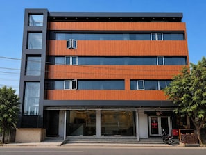 Un immeuble à plusieurs étages doté d’un design moderne, caractérisé par une combinaison d’éléments de façade en verre et en bois.