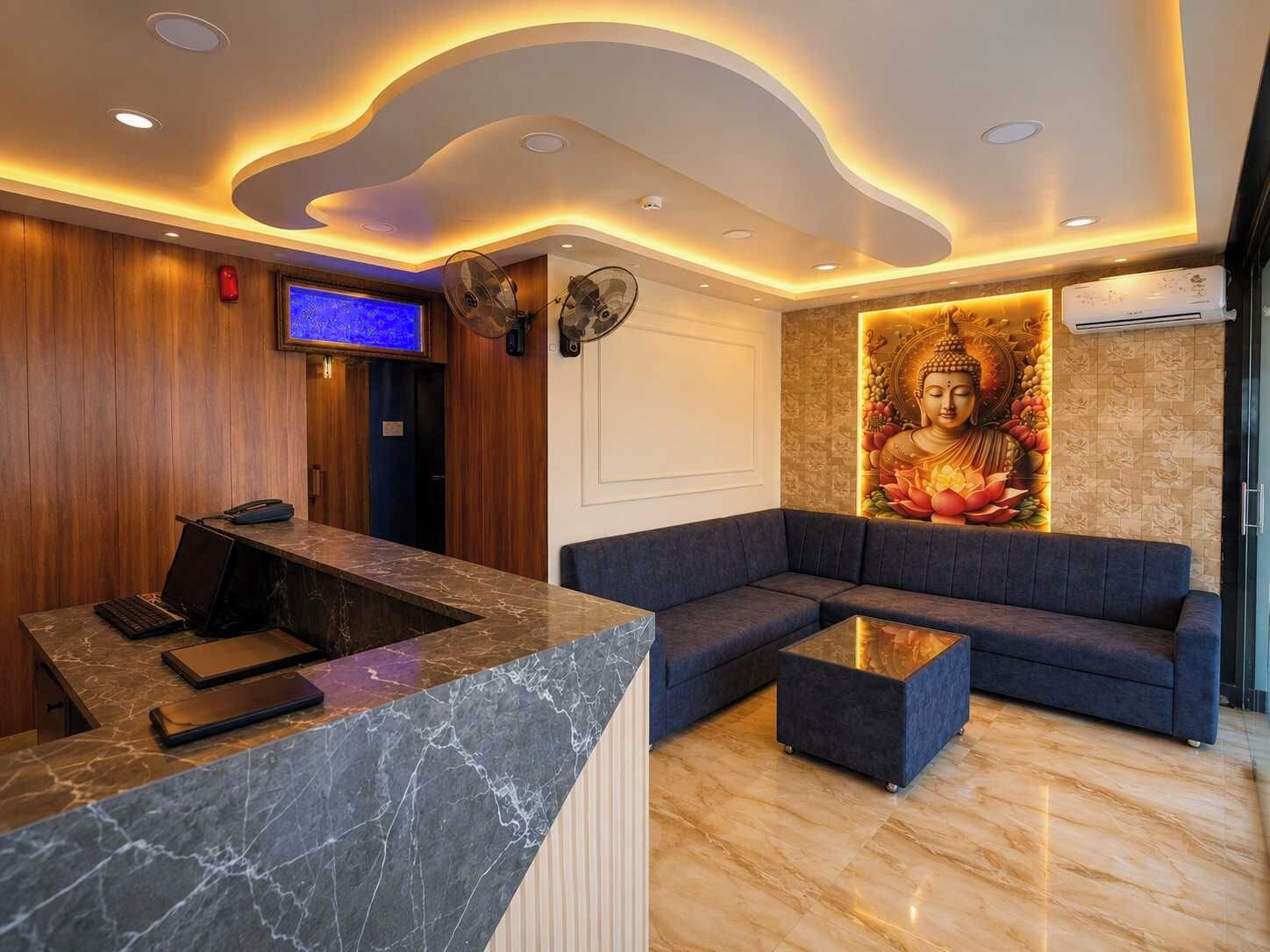 A reception area with a marble counter, a blue sofa, and a Buddha mural.