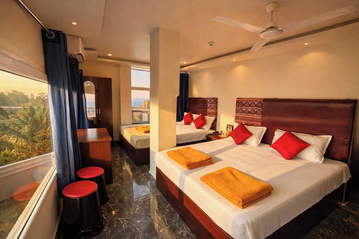 A hotel room with two beds, a desk, and a view of the city.
