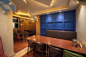 A restaurant interior with a long table, multiple chairs, and a blue accent wall. - Hotel O Pearl Marine (Port-Blair)