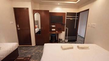 Habitación de hotel con dos camas, un escritorio, un espejo, un armario y baño.