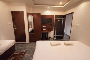 Une chambre d’hôtel avec deux lits, un bureau, un miroir, une armoire et une salle de bain.