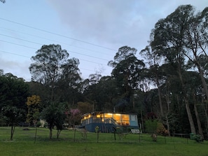 A two-story building with a balcony, surrounded by trees and a fenced area. - Forest Cottage Bed-n-breakfast (Reefton)