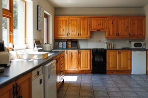 Una cocina con armarios de madera, lavavajillas, estufa y microondas.