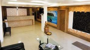 A hotel reception area with a reception desk, a statue, and a wall with a tropical mural. - Hotel O Seagull (Port-Blair)