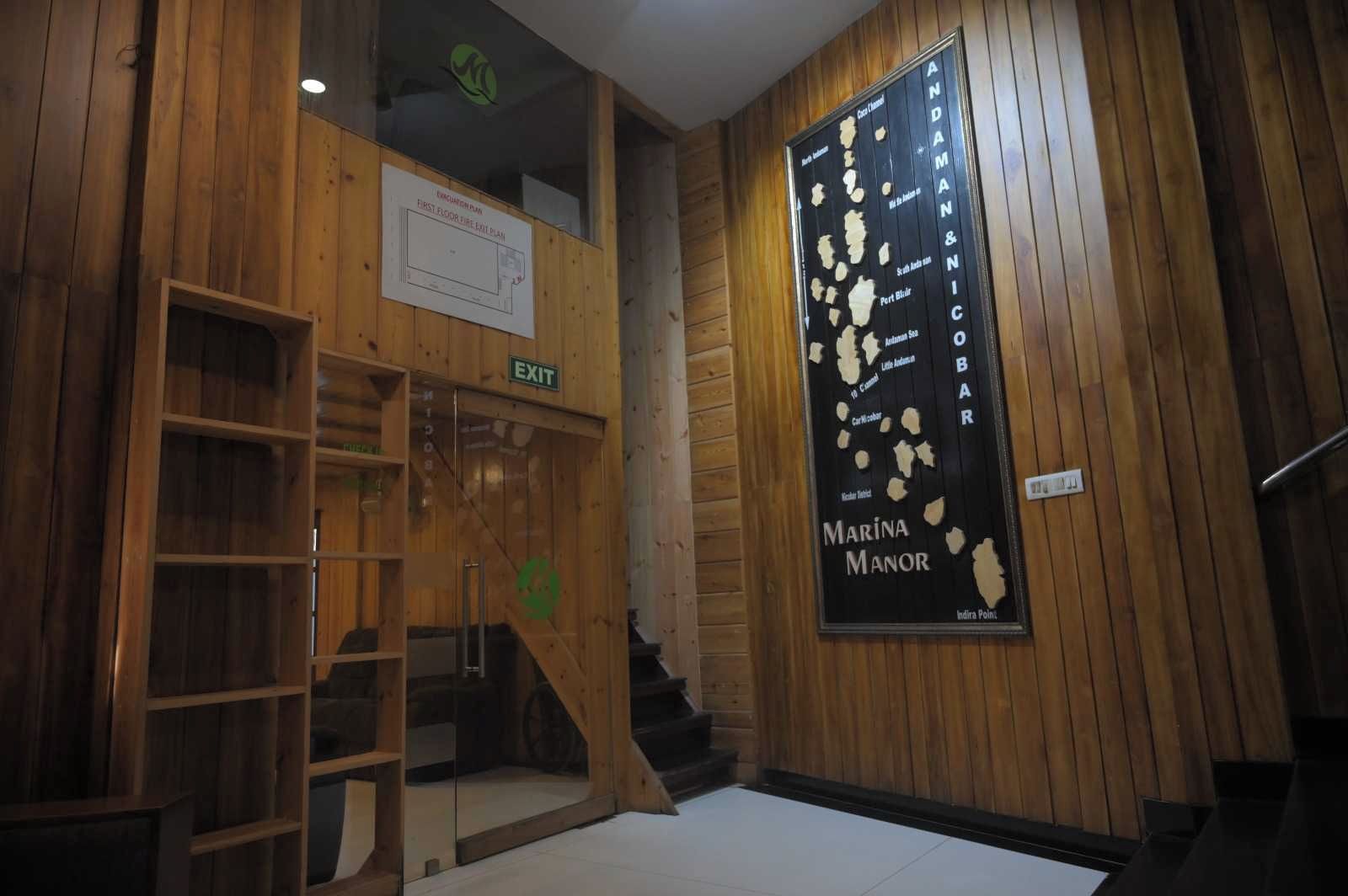 Un interior de madera con una escalera, un cartel del Marina Manor y una señal de salida.