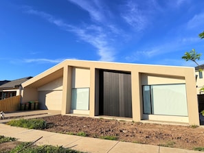 A modern two-story house with a sloped roof, large windows, and a well-maintained garden.