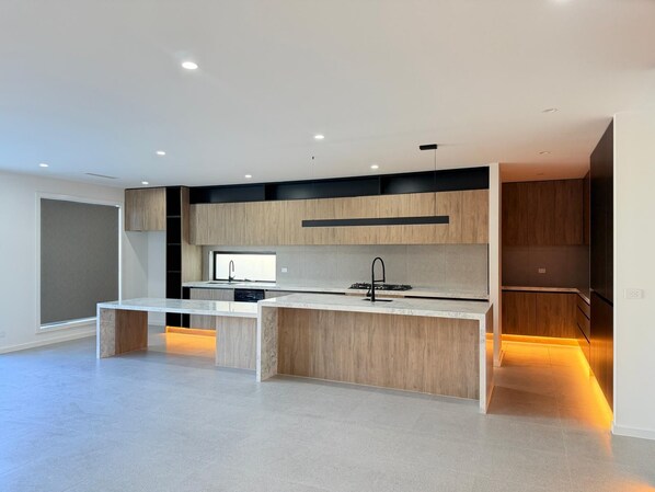 A modern kitchen with a central island, built-in appliances, and a large window.
