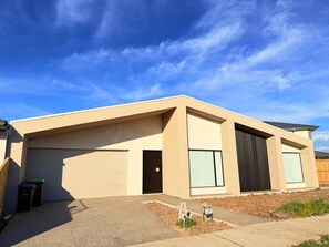 A modern two-story house with a garage, large windows, and a sloped roof.
