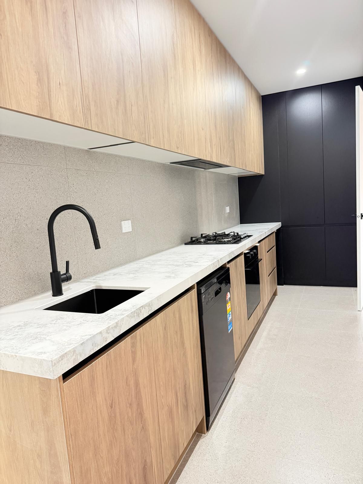 A modern kitchen with wooden cabinets, a black faucet, and a dishwasher.