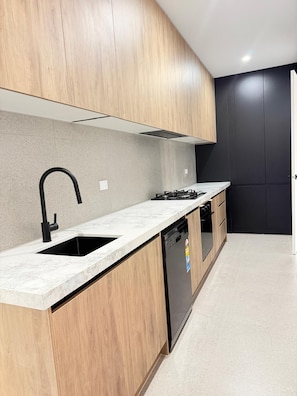 A modern kitchen with wooden cabinets, a black faucet, and a dishwasher.