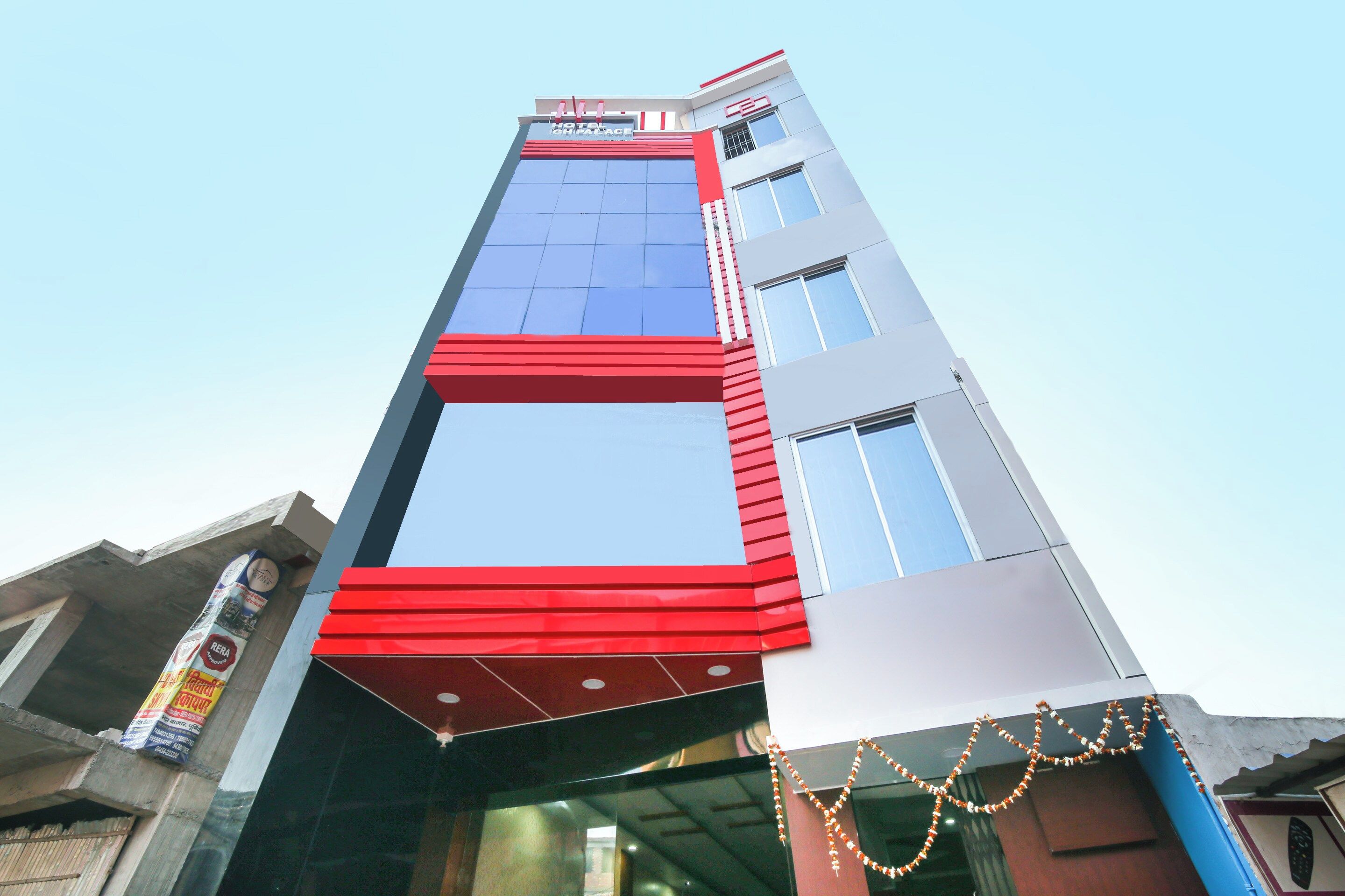 Um edifício moderno de hotel com fachada marcante em vermelho e azul, grandes janelas e uma placa indicando ser um hotel.