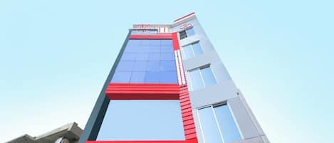 A modern hotel building with a prominent red and blue facade, large windows, and a sign indicating it is a hotel.