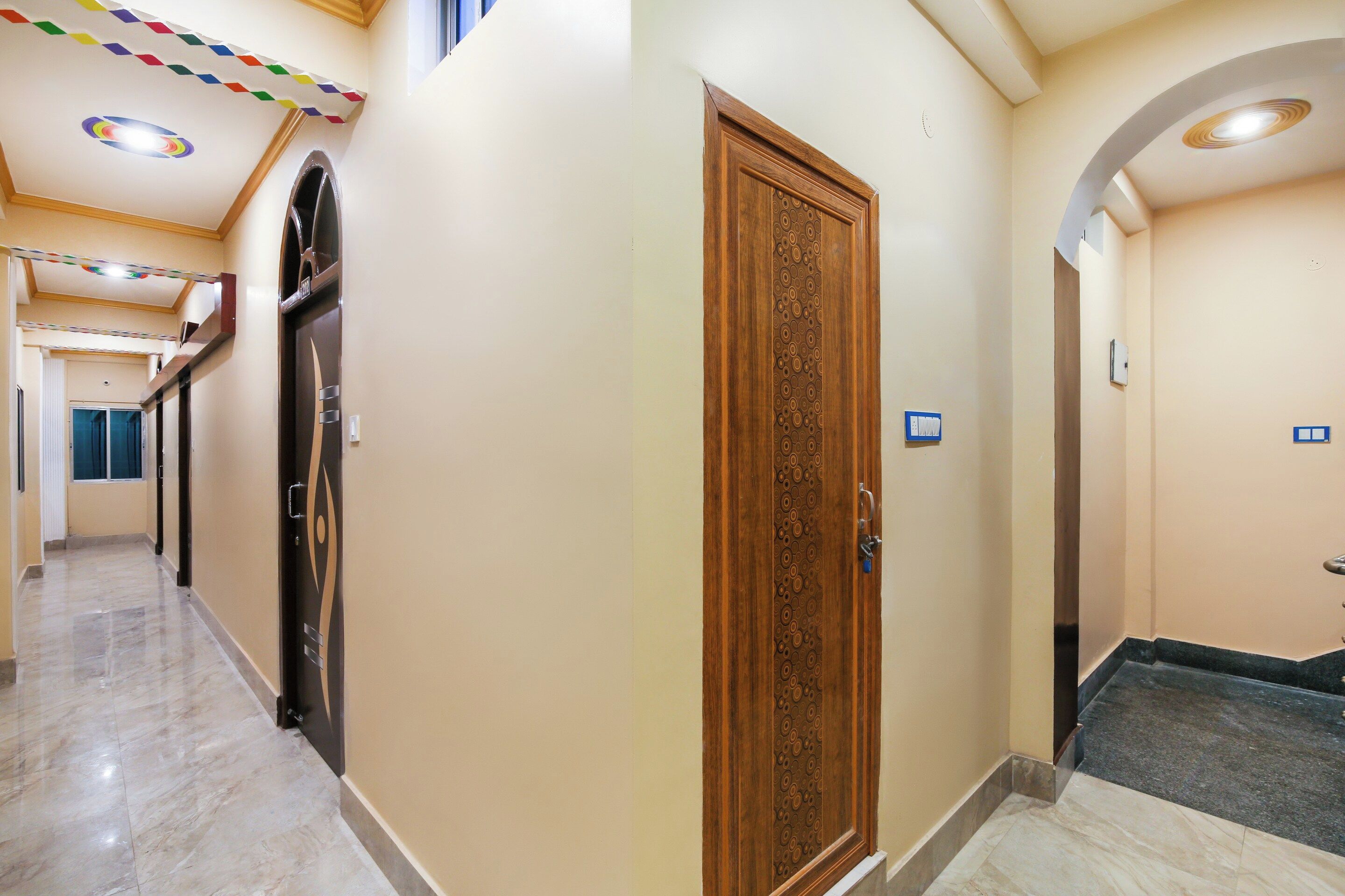 Corredor de hotel com porta de madeira, piso de azulejos e teto com iluminação embutida.