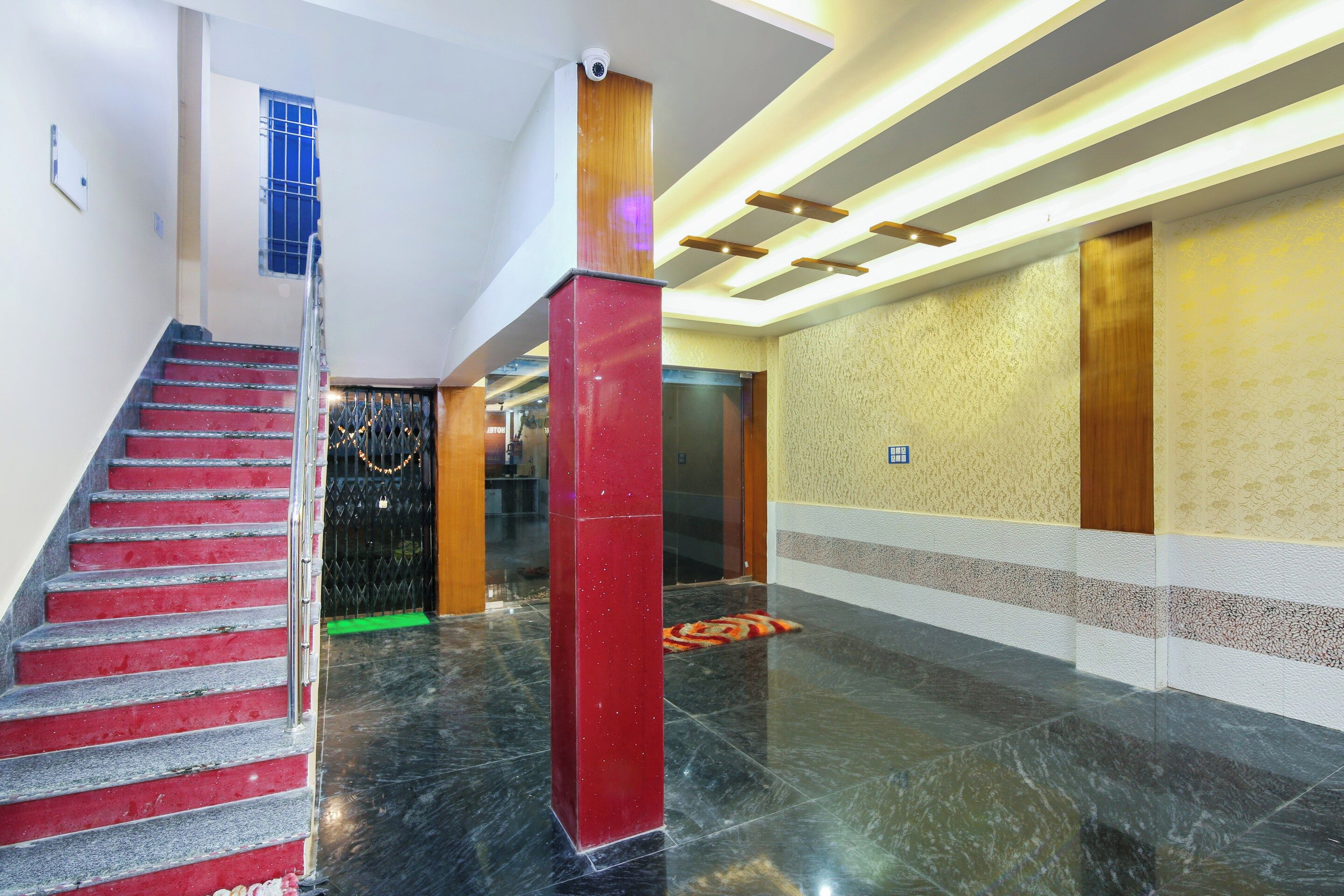 Um hall de hotel com piso de mármore, escadaria e balcão de recepção.
