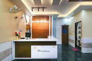 Bancada de recepção com uma placa indicando 'HOTEL SINGH PALACE' e a etiqueta 'Recepção'.