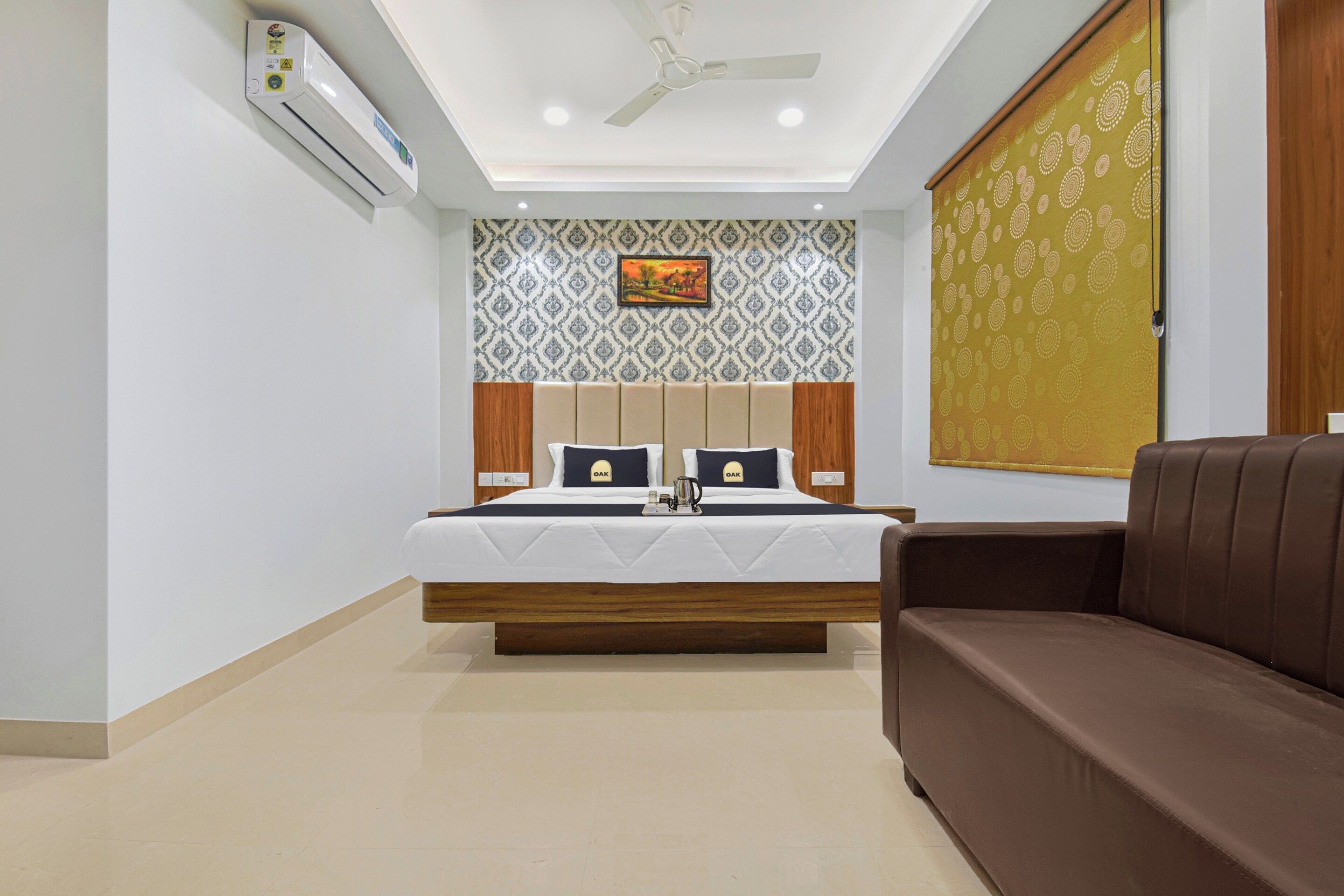 Une chambre d’hôtel équipée d’un lit, d’un canapé, d’un ventilateur de plafond et d’un climatiseur fixé au mur.