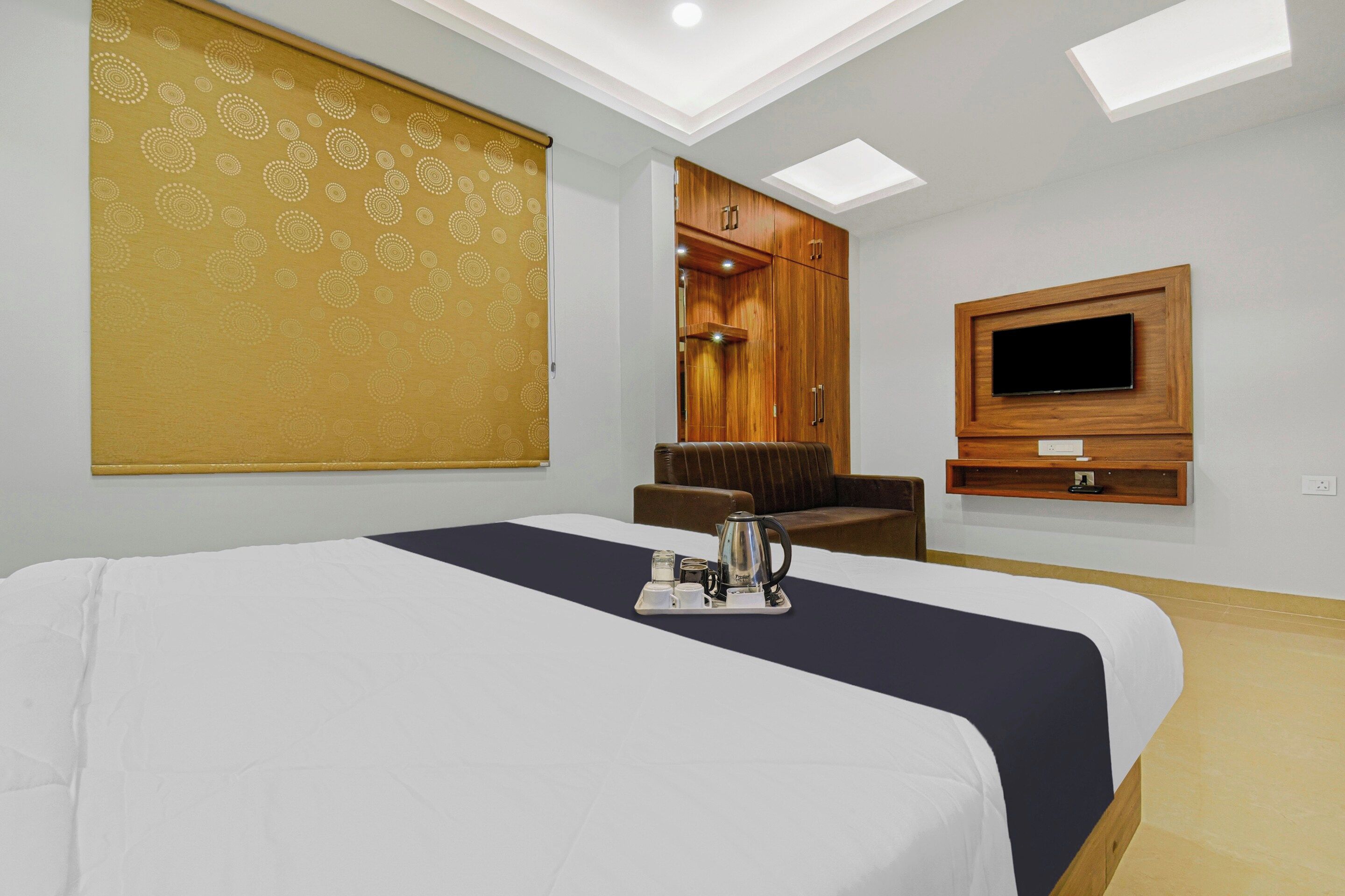 Una habitación de hotel con cama, zona de estar, televisor y armario.