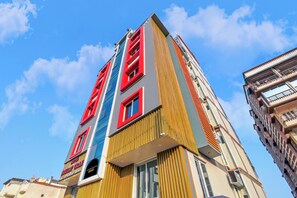 Een hotel met meerdere verdiepingen, met een moderne gevel, kenmerkend met verticale strepen en een opvallend rood logo.