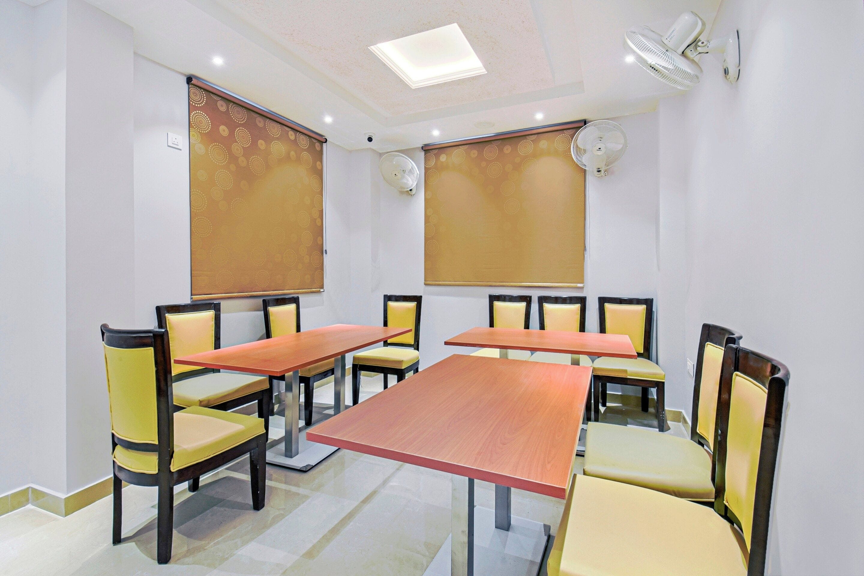 Un salón de conferencias con una larga mesa, sillas y ventiladores de techo.