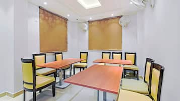 Un salón de conferencias con una larga mesa, sillas y ventiladores de techo.