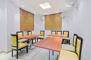 Sala de conferências com uma mesa comprida, cadeiras e ventiladores de teto.