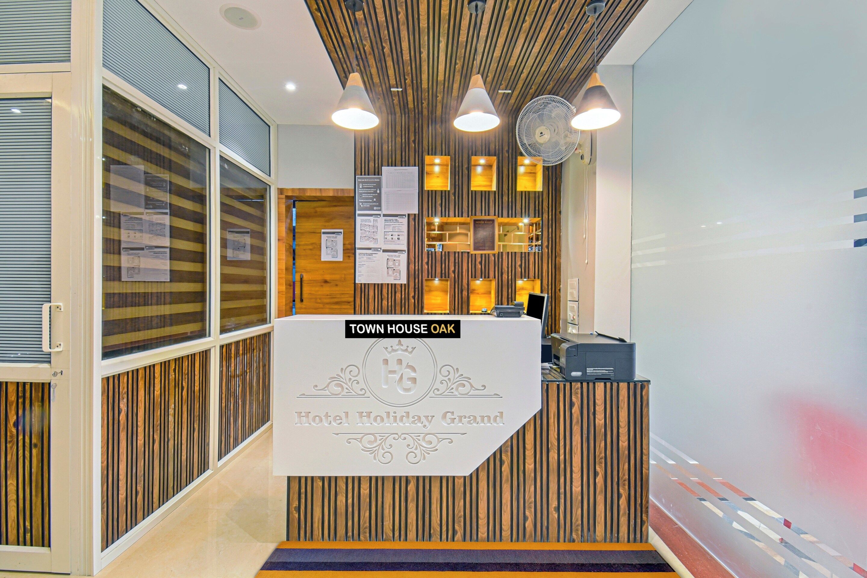 A reception desk with a sign reading 'TOWN HOUSE OAK Hotel Holiday Grand.'