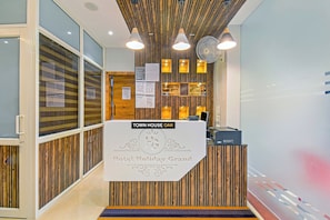 Een receptiebalie met een bord waarop staat 'TOWN HOUSE OAK Hotel Holiday Grand'.